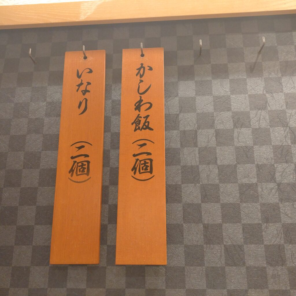 店内に木に書かれた定番メニューがあります。かしわ飯、いなりです。