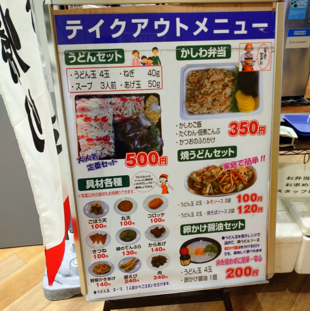 テイクアウトの案内の外看板、かしわ弁当（かしわご飯、たくわん・佃煮こんぶ、かつおのふりかけ）350円、うどんセット（うどん4玉、ねぎ40g、スープ3人前、あげ玉50g）500円ほか